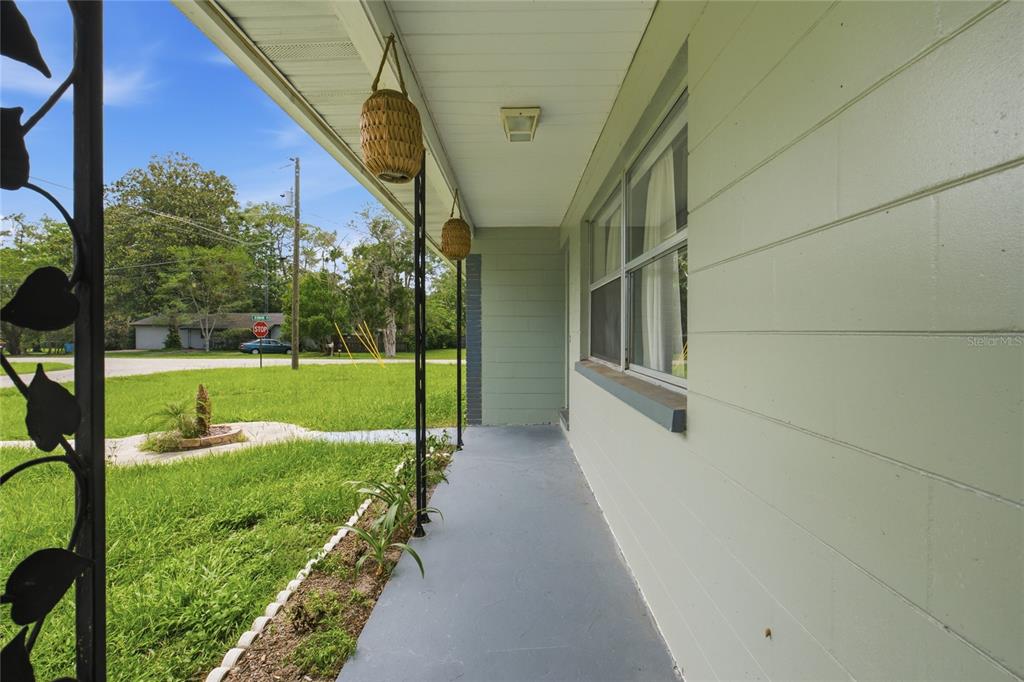 A view from a covered front porch looking out toward a grassy yard and street — 5307 SE 108TH STREET, BELLEVIEW, FL
