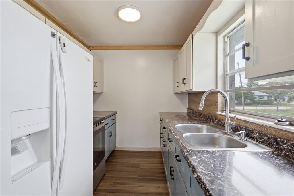 A kitchen features white cabinets, blue lower cabinets, dark countertops, and a stainless steel sink — 5307 SE 108TH STREET, BELLEVIEW, FL