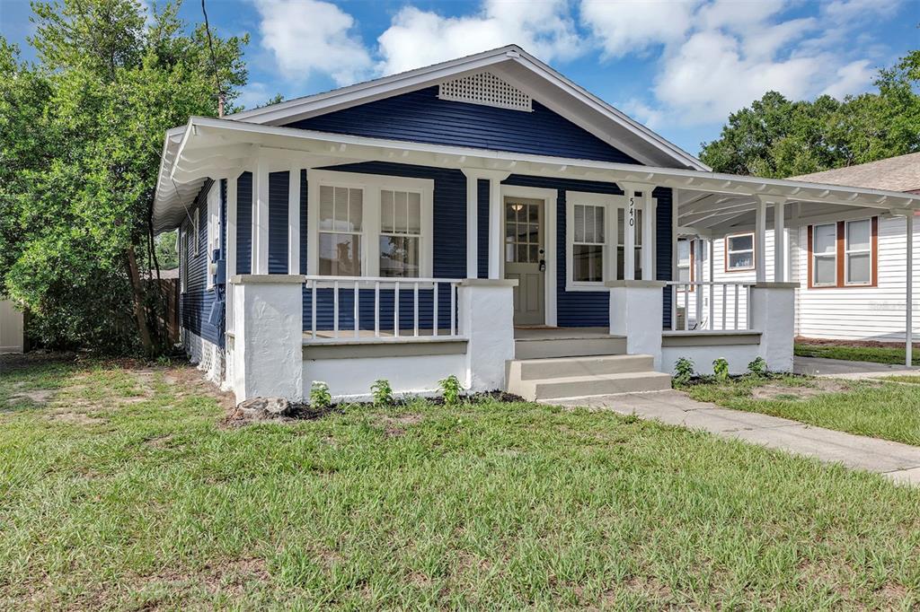 A blue bungalow with a white porch and white trim sits on a grassy lot — 540 W HANCOCK STREET, LAKELAND, FL