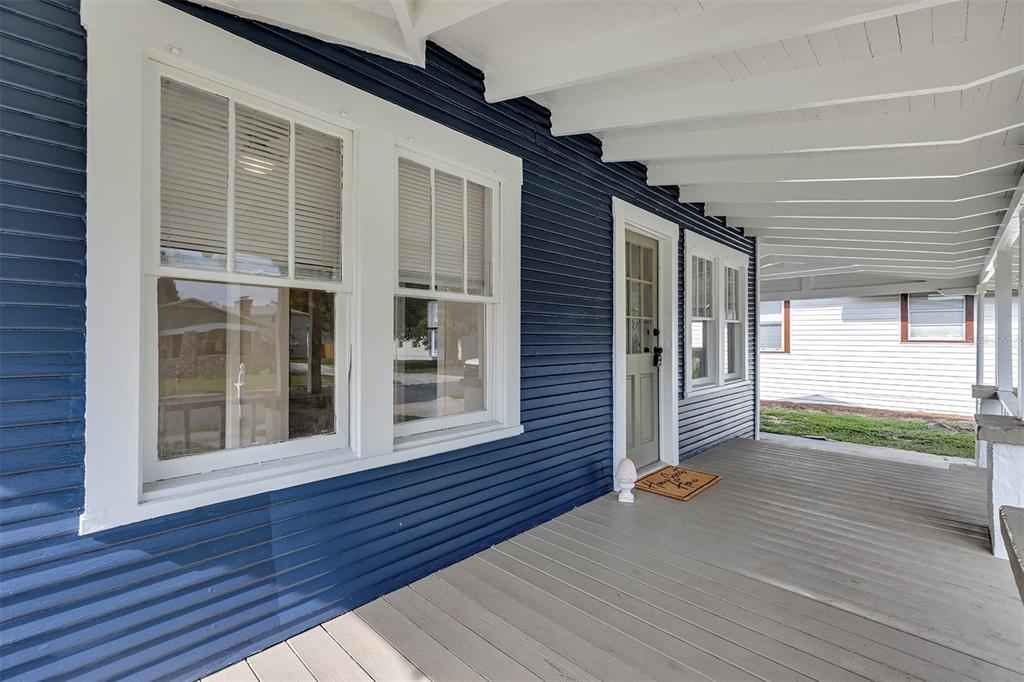 A covered porch with blue horizontal siding, white trim, and a light-colored wooden floor — 540 W HANCOCK STREET, LAKELAND, FL