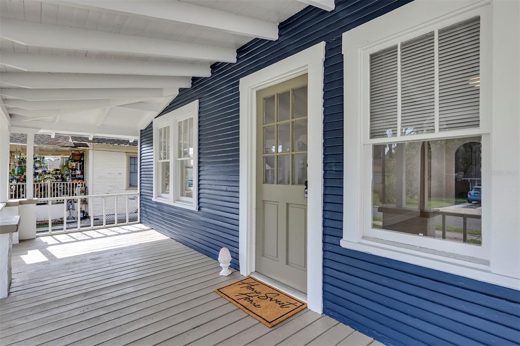 A covered porch with blue siding, a light-colored door, and a wooden floor — 540 W HANCOCK STREET, LAKELAND, FL