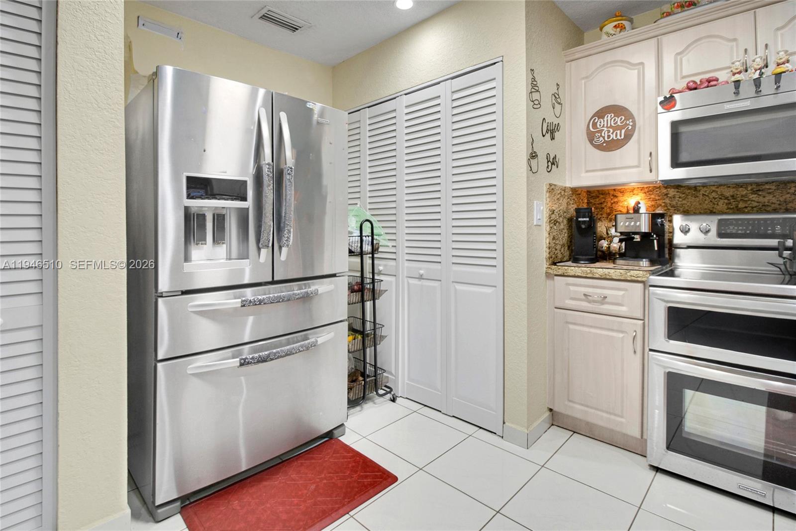 A kitchen features stainless steel appliances, white louvered doors, and a dedicated coffee bar area — 42 NW 132nd Pl, Miami FL 33182, MIAMI, FL