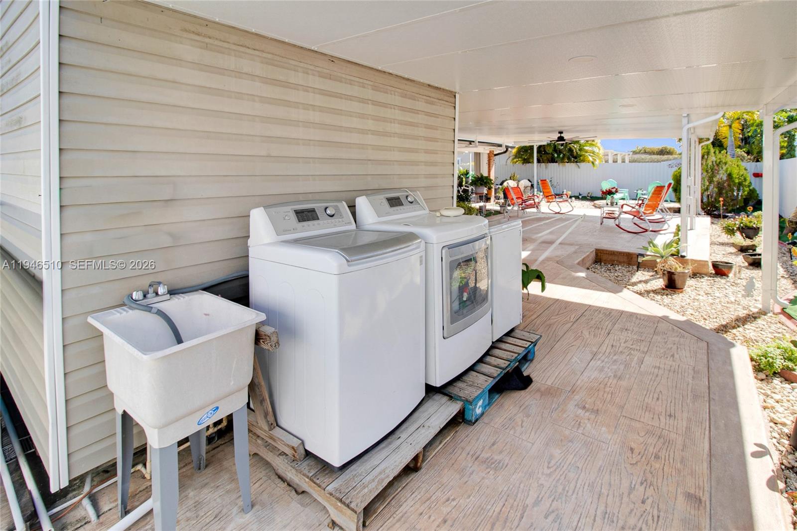 A laundry area with a utility sink and appliances sits on a covered outdoor patio — 42 NW 132nd Pl, Miami FL 33182, MIAMI, FL