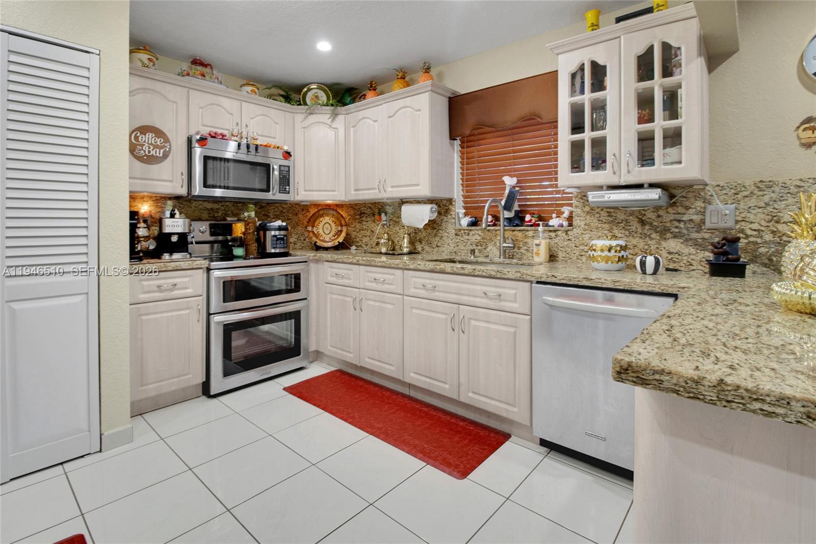 A kitchen features light wood cabinets, granite countertops, stainless steel appliances, and white tile flooring — 42 NW 132nd Pl, Miami FL 33182, MIAMI, FL