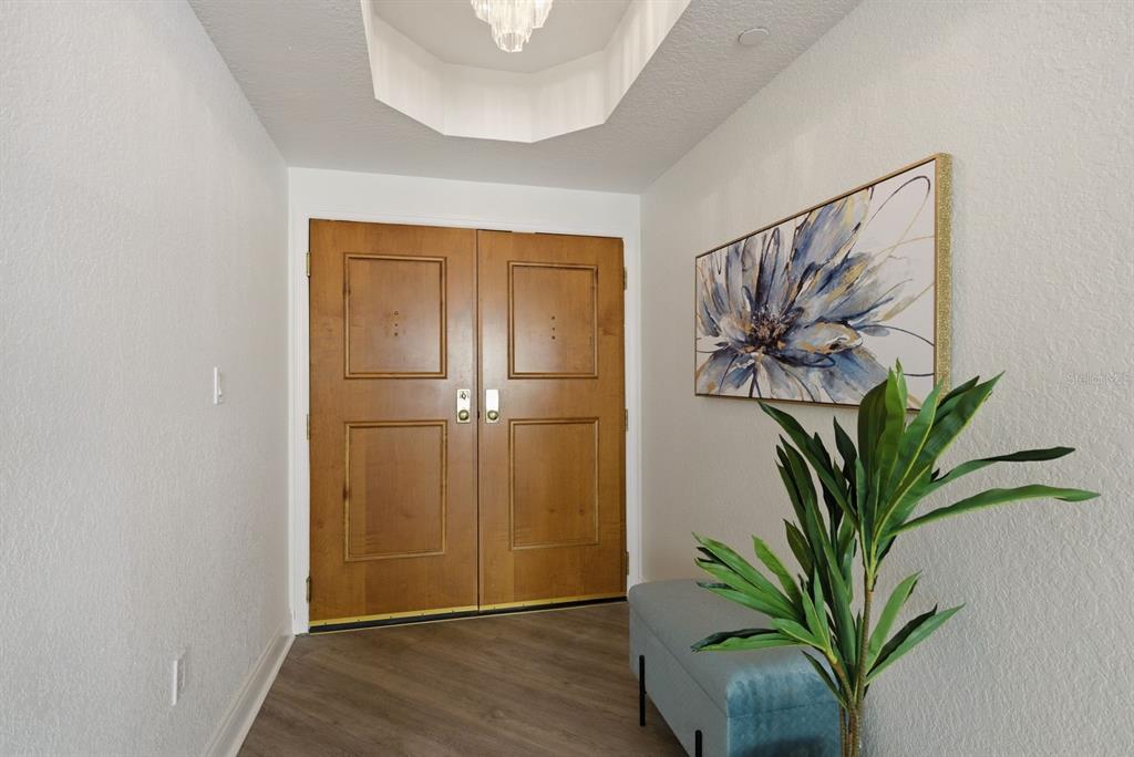 An entryway features double wooden doors, a light blue bench, and a floral wall painting — 1170 SE GULF BOULEVARD UNIT 305, CLEARWATER BEACH, FL