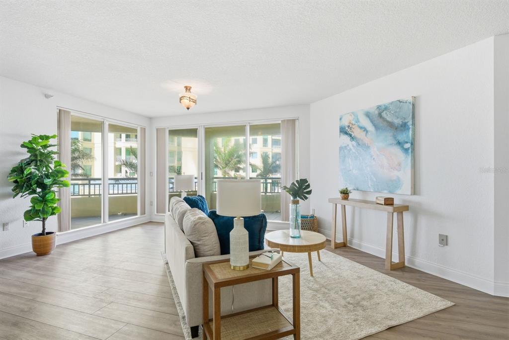 A living room features light wood-look flooring, a sofa, a console table, and balcony access — 1170 SE GULF BOULEVARD UNIT 305, CLEARWATER BEACH, FL