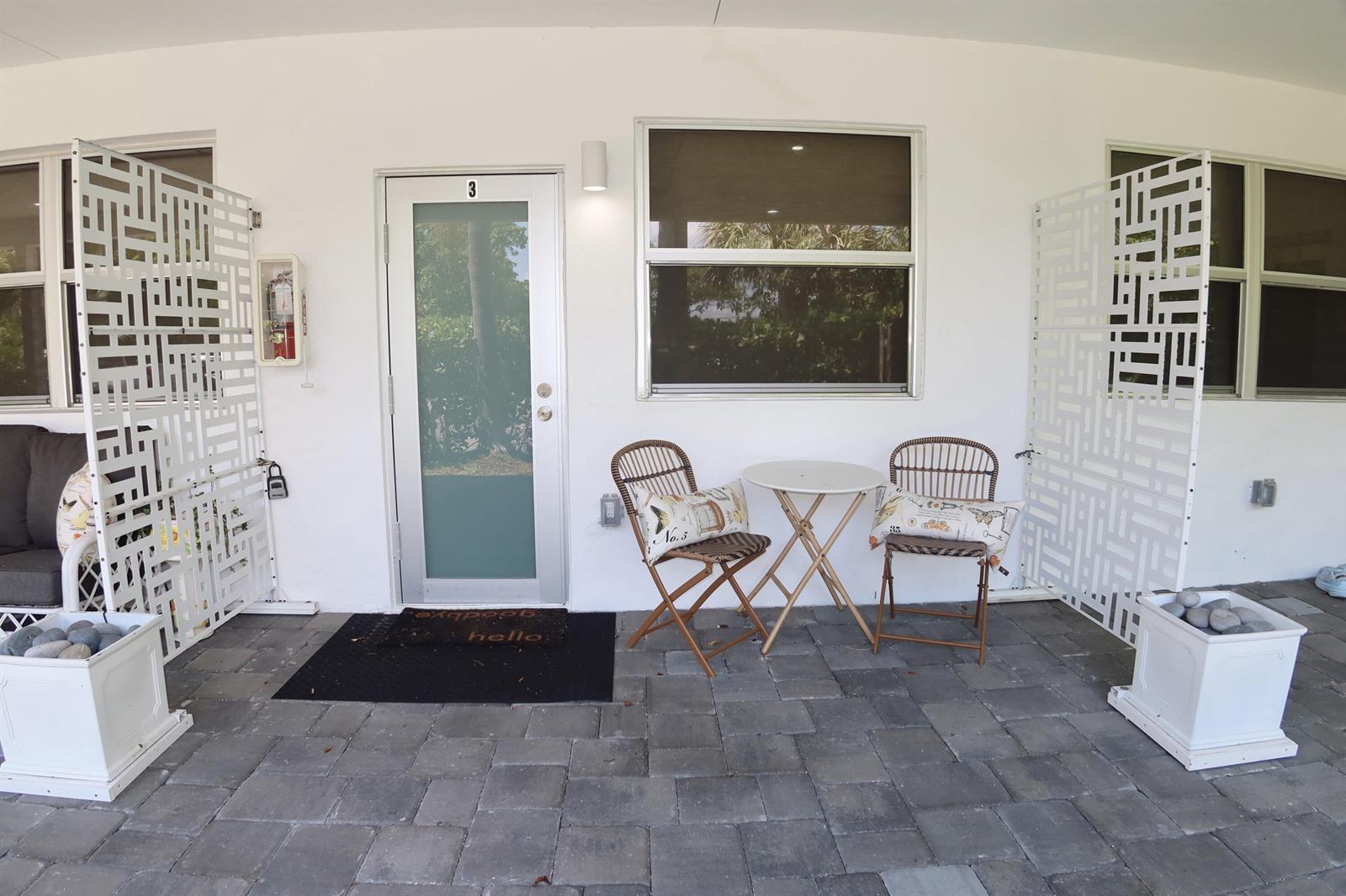A patio features a glass door, two chairs with a small table, and privacy screens — 3408 Spring Street # 3, Pompano Beach FL 33062, POMPANO BEACH, FL