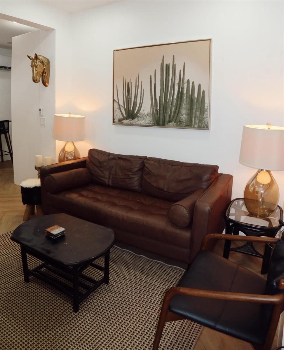 A living room features a brown leather sofa, a black coffee table, and cactus wall art — 3408 Spring Street # 3, Pompano Beach FL 33062, POMPANO BEACH, FL