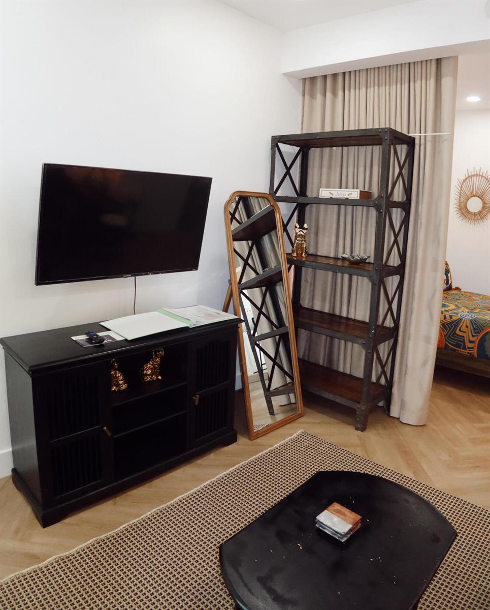 A living room features a wall-mounted television, a black media console, a floor mirror, and shelving — 3408 Spring Street # 3, Pompano Beach FL 33062, POMPANO BEACH, FL