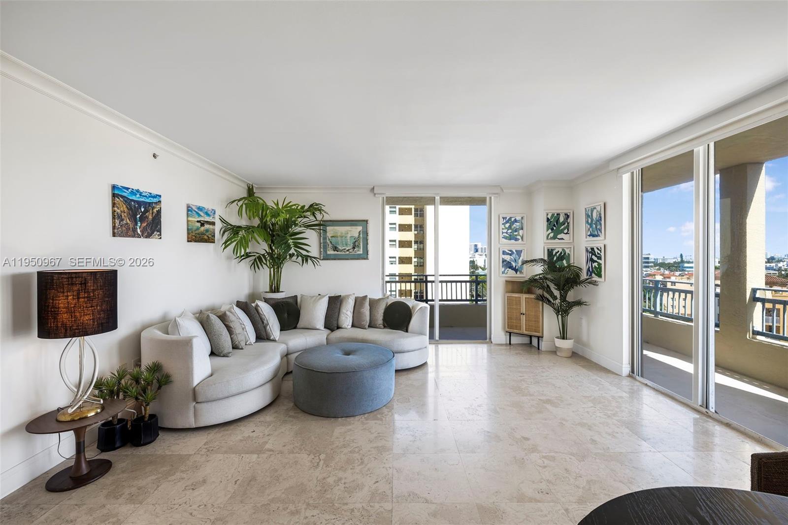 A bright living room features a curved sectional sofa, a blue ottoman, and marble flooring — 90 Alton Rd # 811, Miami Beach FL 33139, MIAMI BEACH, FL