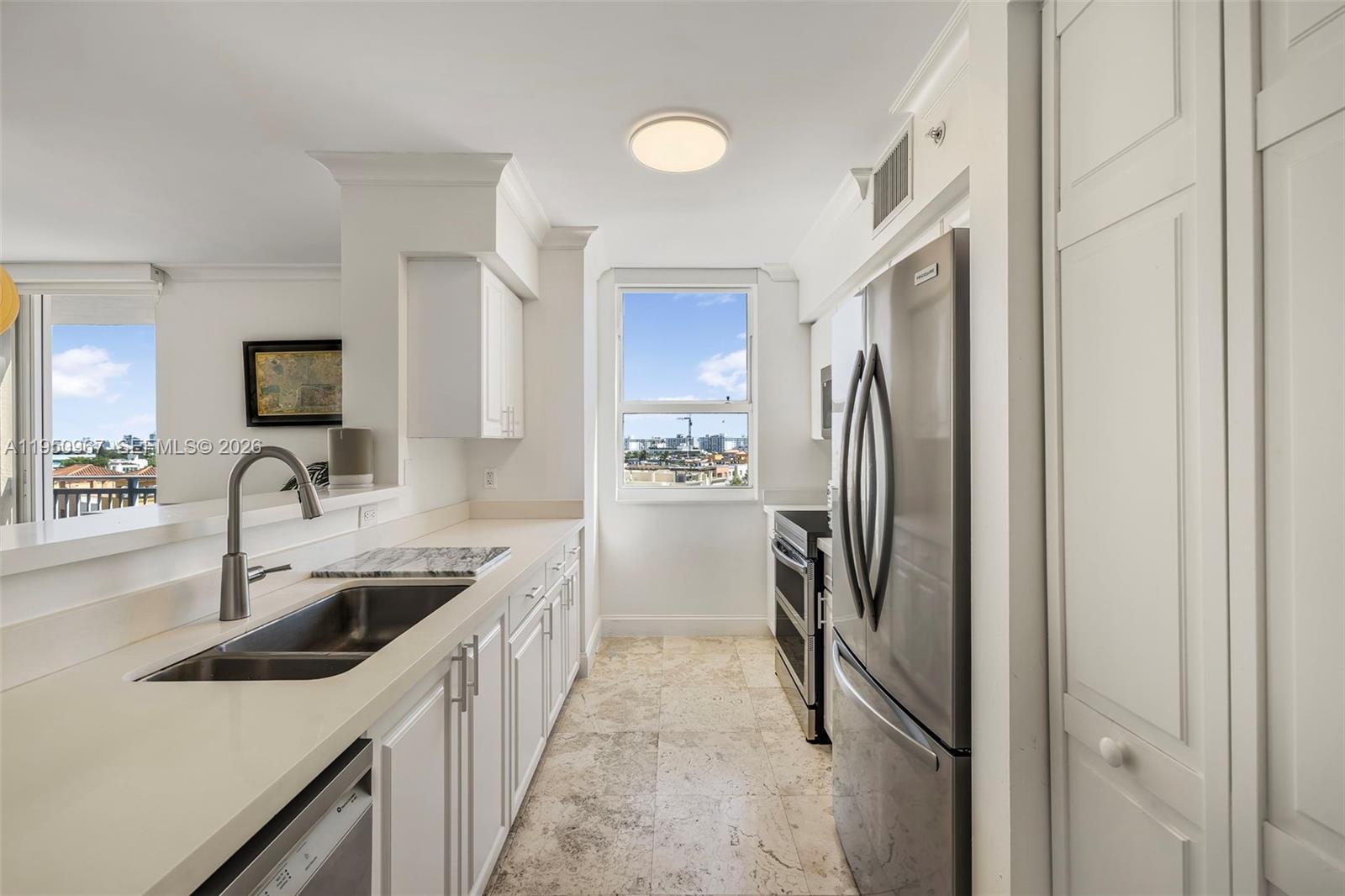 A galley kitchen features white cabinets, stainless steel appliances, and a window with city views — 90 Alton Rd # 811, Miami Beach FL 33139, MIAMI BEACH, FL