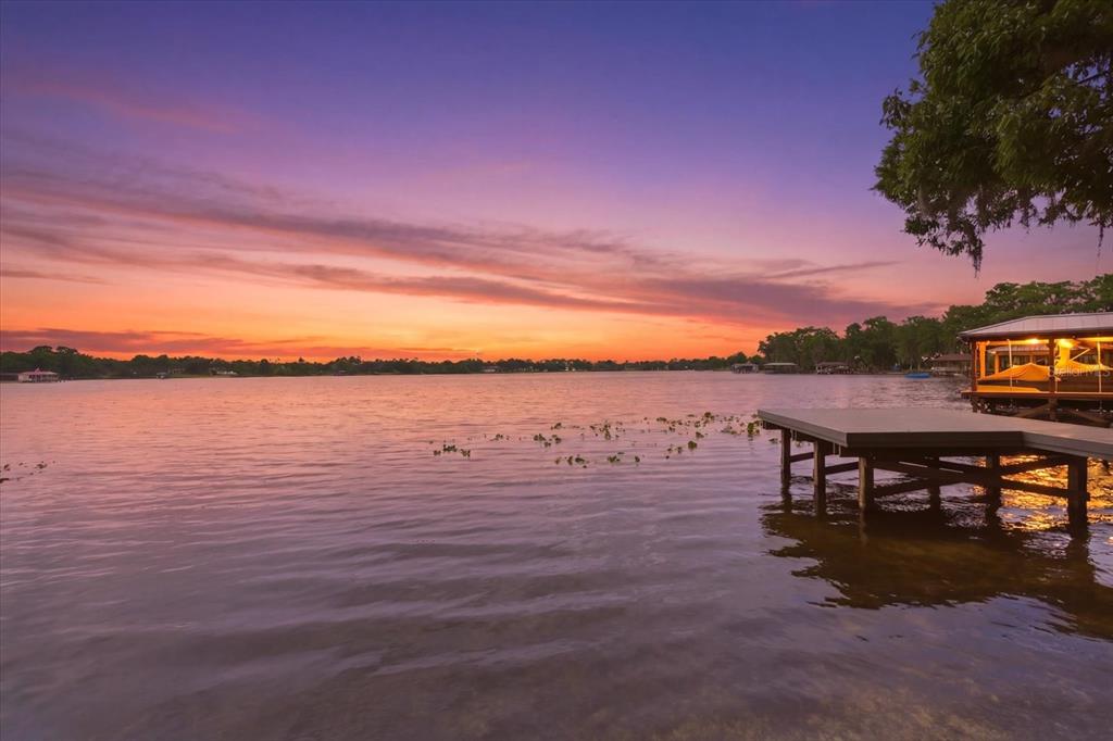 A wooden dock extends into a calm lake under a vibrant sunset sky — 4910 E LAKE DRIVE, WINTER SPRINGS, FL