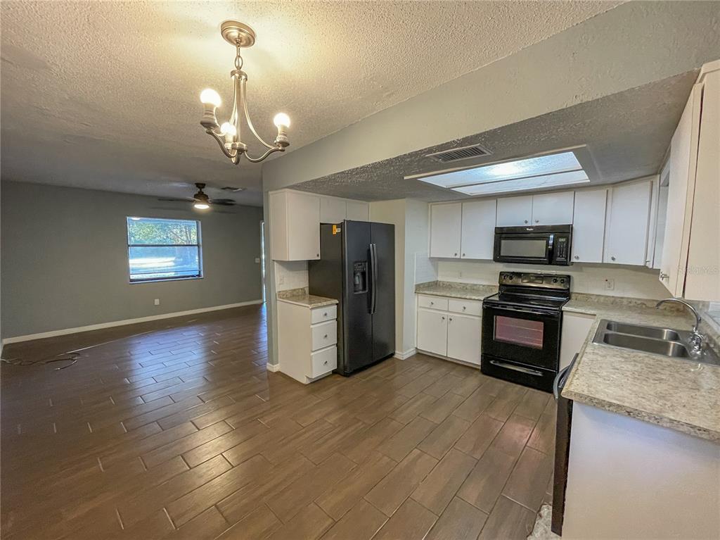 A screened-in patio features a long dining table, wicker chairs, and a grill — 9875 W ORCHARD STREET, CRYSTAL RIVER, FL
