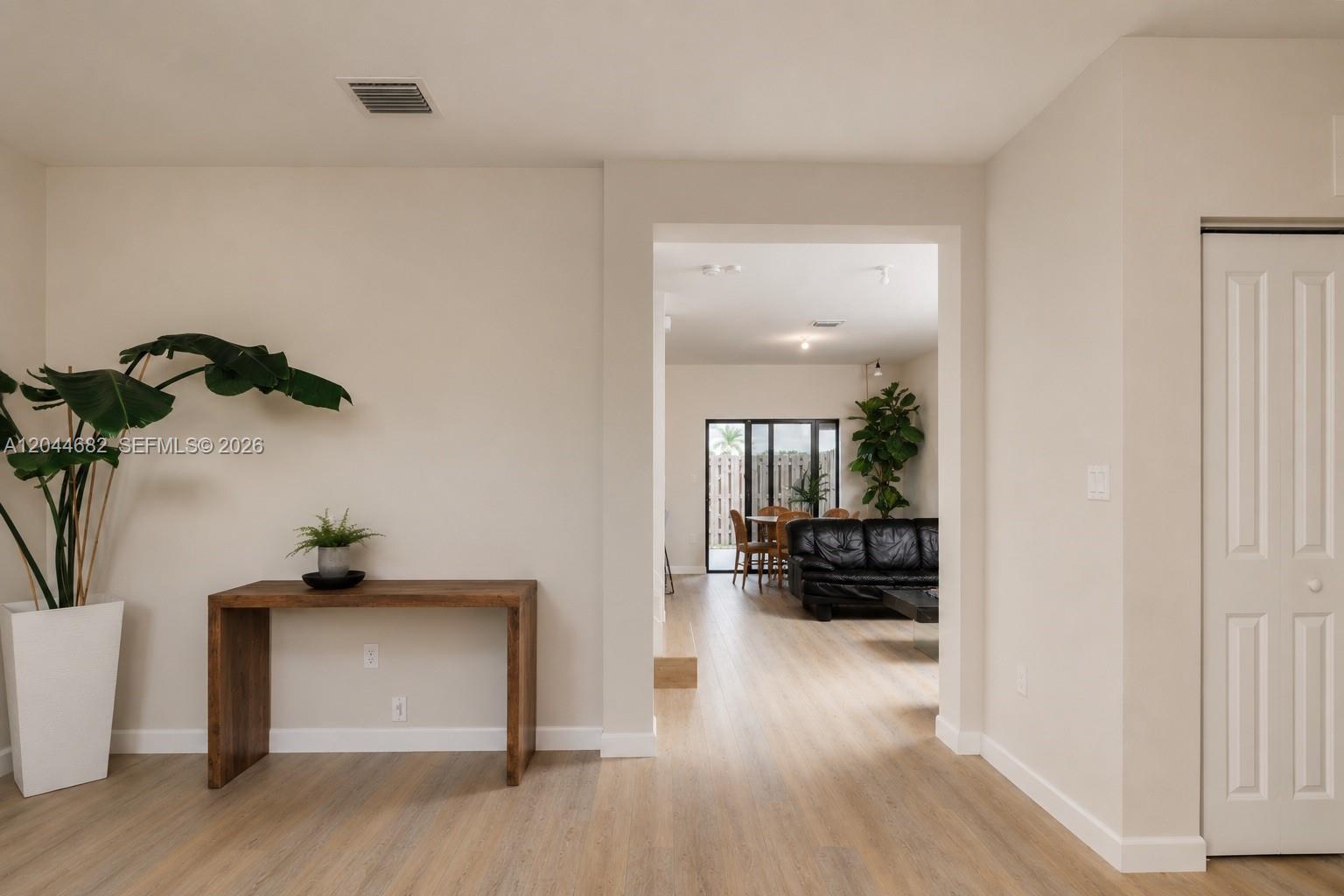 A wooden console table and potted plant sit in a hallway leading to a living area — 10079 SW 228 # 10079, Miami FL 33190, MIAMI, FL