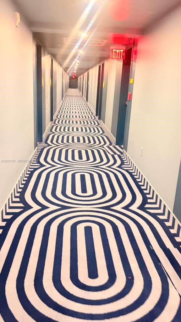 A long hotel hallway features blue and white geometric patterned carpet and multiple closed doors — 90 NE 32nd St # 624, Miami FL 33137, MIAMI, FL