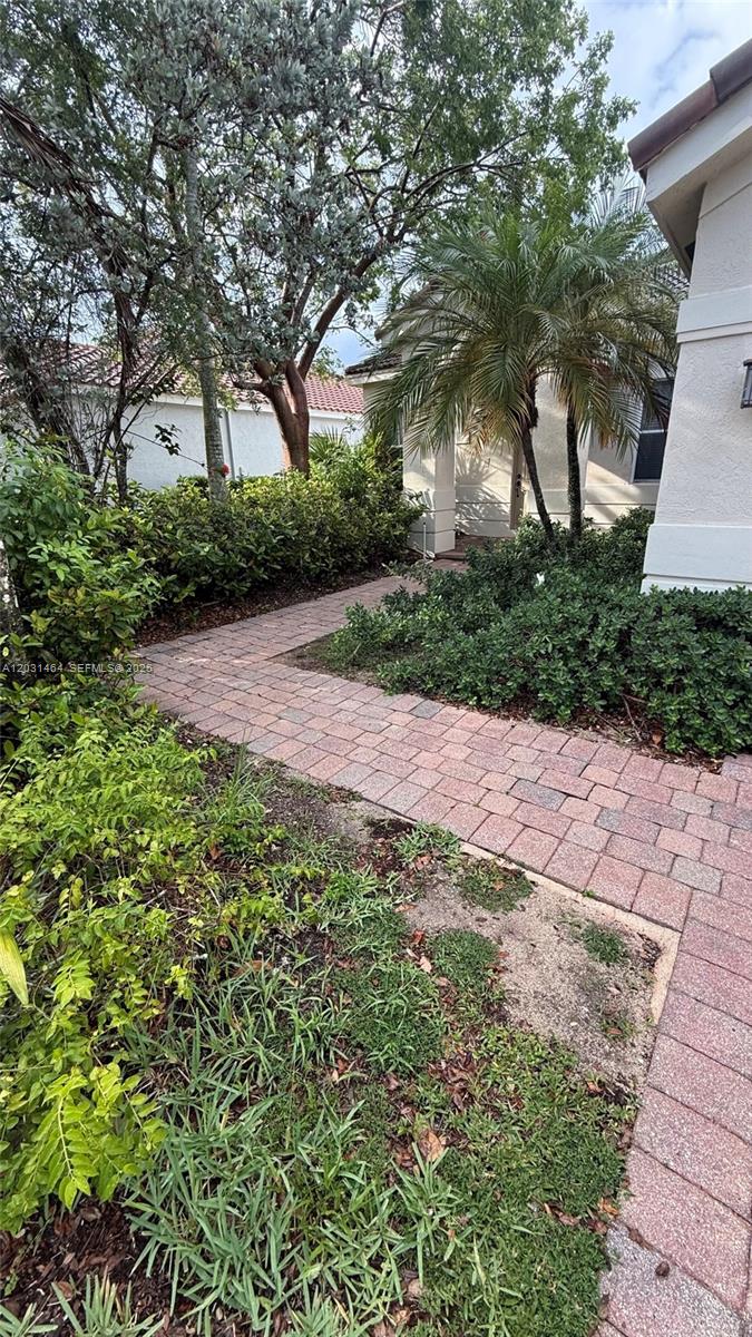 A brick paver walkway leads toward the entrance of a house surrounded by landscaping — 748 Tulip Cir, Weston FL 33327, WESTON, FL