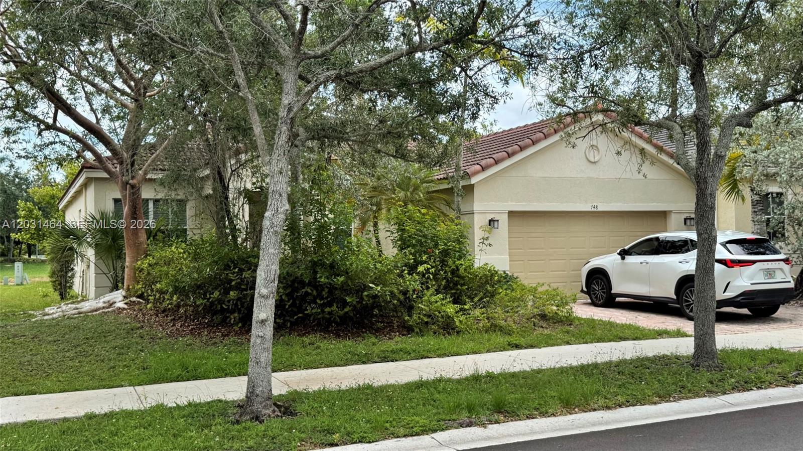 A single-story house with a tiled roof, a two-car garage, and a white SUV parked outside — 748 Tulip Cir, Weston FL 33327, WESTON, FL