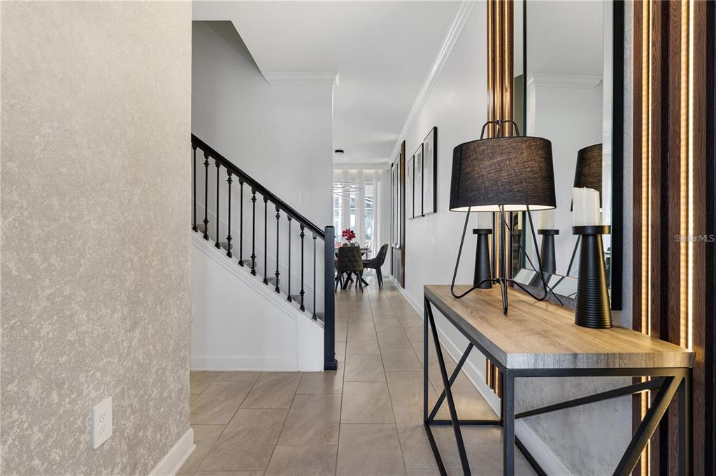 A hallway features a console table, a staircase with black railings, and light tile flooring — 1146 KINGSBARN STREET, DAVENPORT, FL