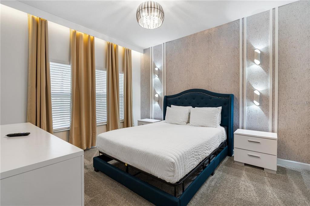 A bedroom features a blue tufted headboard, gold curtains, and wall-mounted accent lighting — 1146 KINGSBARN STREET, DAVENPORT, FL
