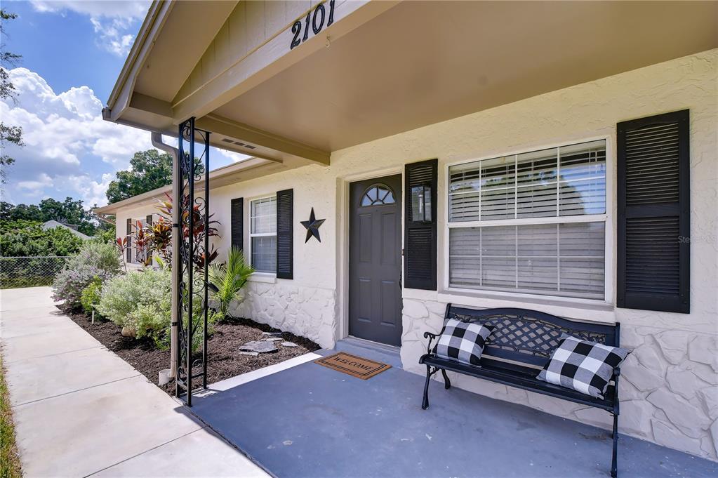 A front porch features a dark gray door, black shutters, and a black metal bench — 2101 W HAMILTON AVENUE, TAMPA, FL