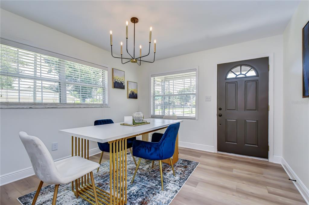 A dining room features a white table, blue velvet chairs, a chandelier, and a front door — 2101 W HAMILTON AVENUE, TAMPA, FL