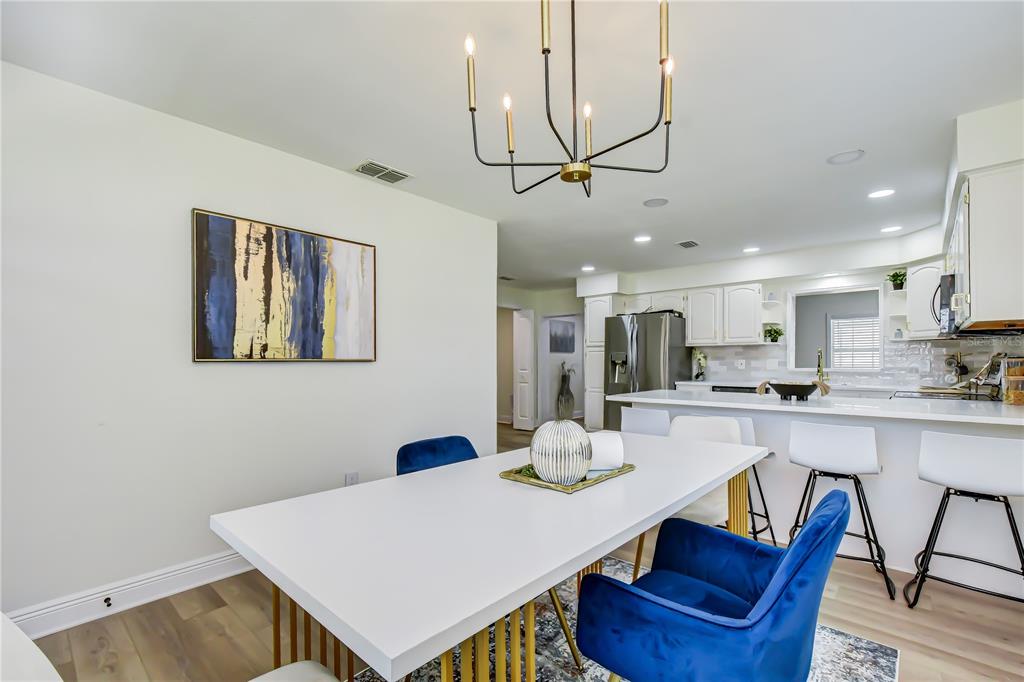 A dining area with a white table and blue chairs sits next to a kitchen — 2101 W HAMILTON AVENUE, TAMPA, FL