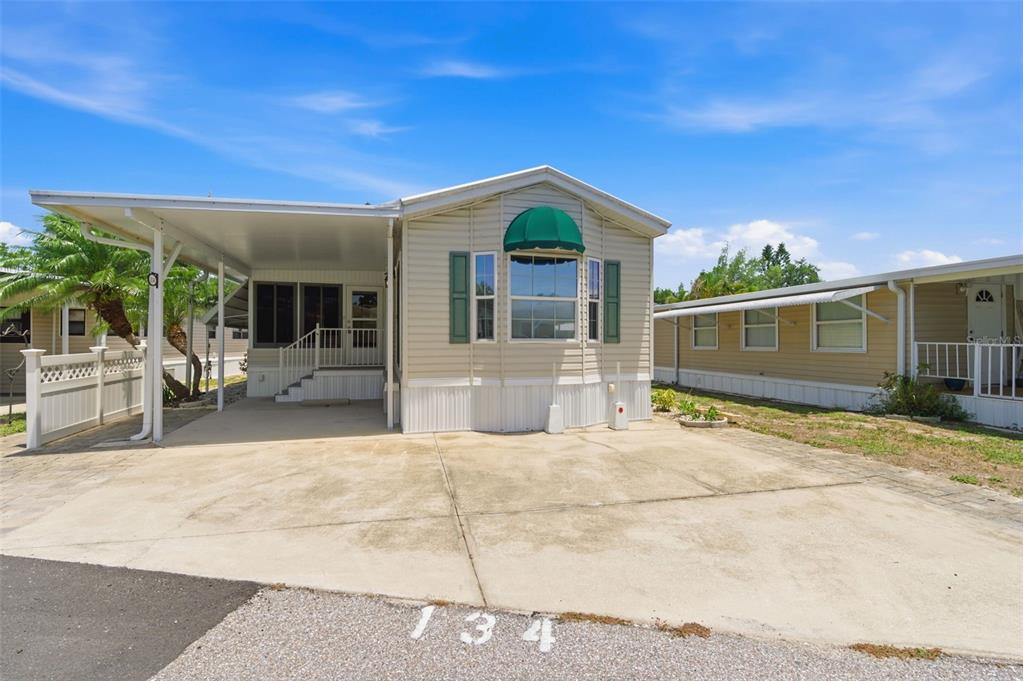 A single-story manufactured home with a carport and a concrete driveway — 3275 26TH AVENUE E UNIT 134, BRADENTON, FL