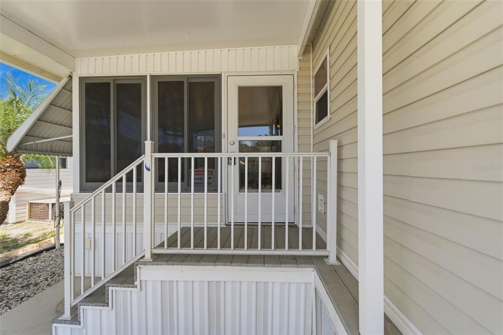 A white-railed porch leads to a glass storm door on a light-colored mobile home — 3275 26TH AVENUE E UNIT 134, BRADENTON, FL