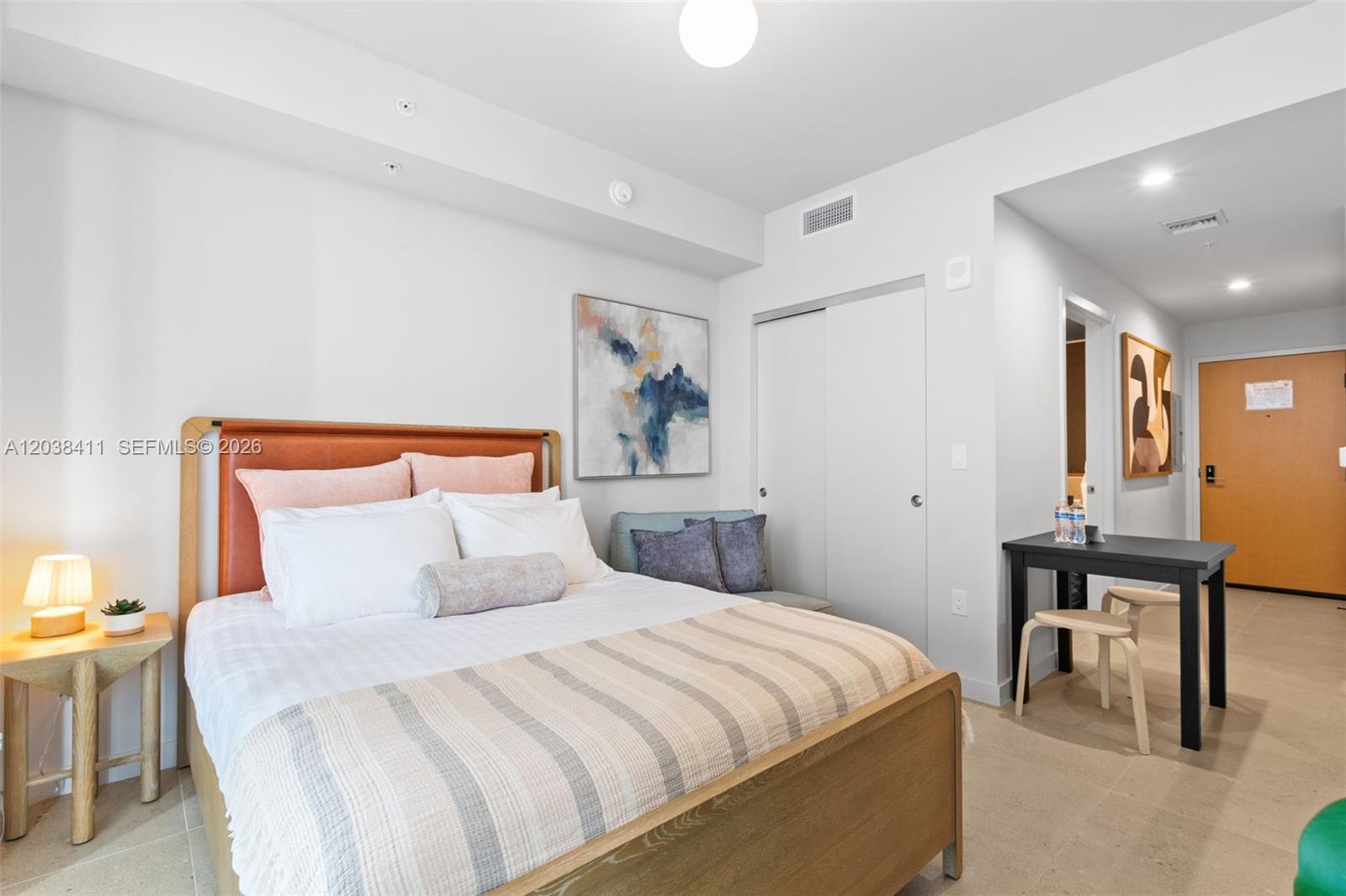 A bedroom features a wooden bed frame, a small dining table, and a sliding closet — 11 NE 6th St # 2406, Miami FL 33132, MIAMI, FL