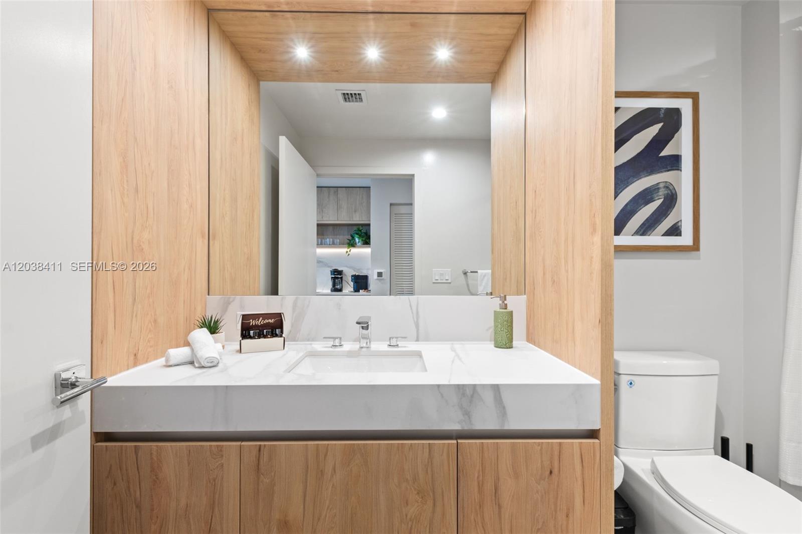 A modern bathroom features a marble vanity, light wood cabinetry, and a large mirror — 11 NE 6th St # 2406, Miami FL 33132, MIAMI, FL
