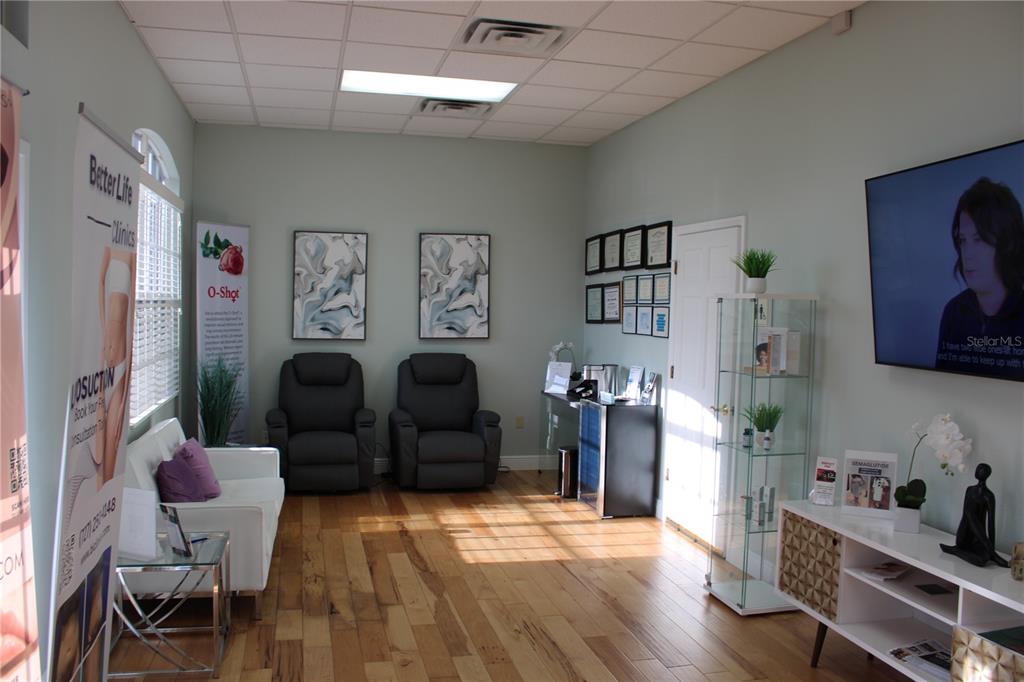 A waiting room features wood flooring, two gray recliners, a white sofa, and a television — 2835 ALT 19 HIGHWAY, PALM HARBOR, FL