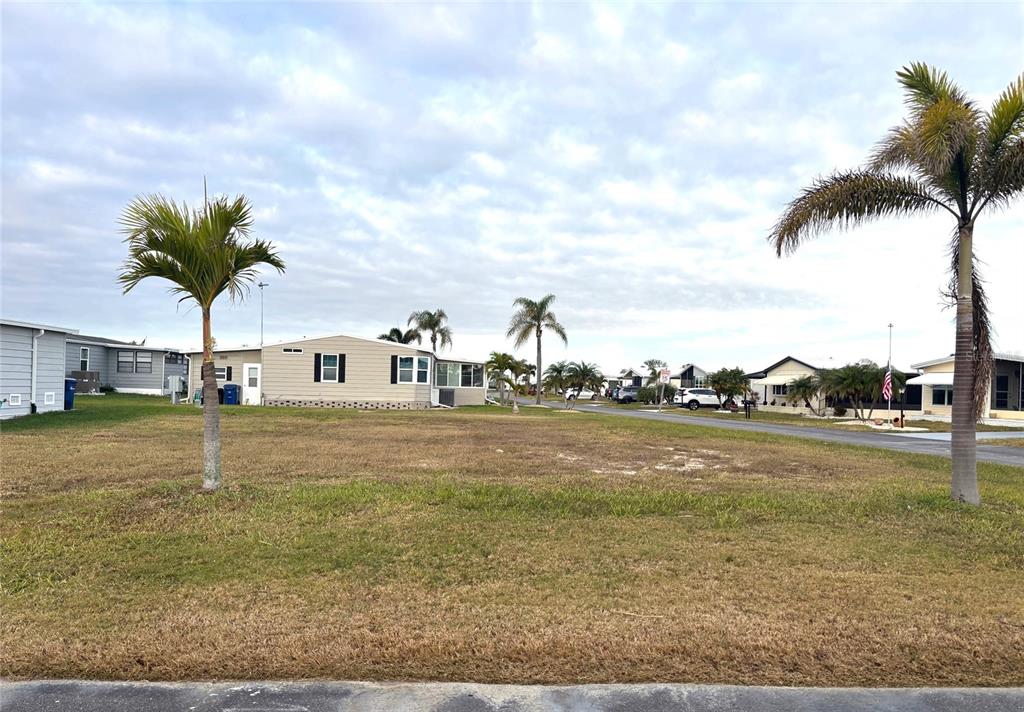 A vacant, grassy lot sits between two palm trees in a residential mobile home community — 501 SAN CLEMENTE CIRCLE, NORTH PORT, FL