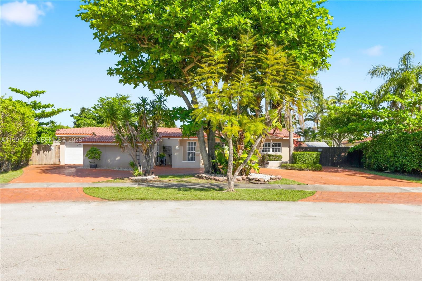 A single-story house with a terracotta-tiled roof and a large circular paved driveway — 9955 SW 74th St, Miami FL 33173, MIAMI, FL