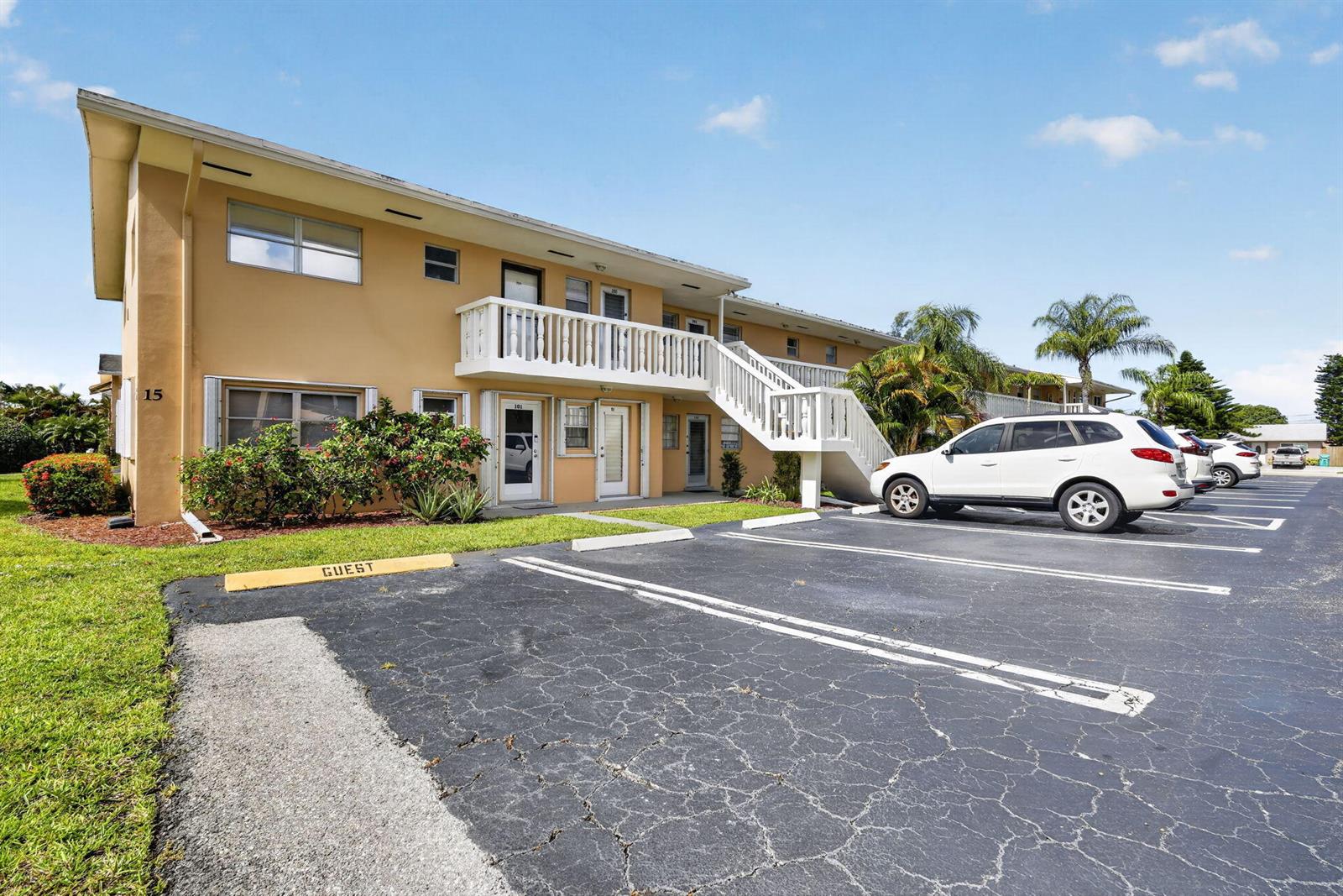 A two-story tan apartment building features a white exterior staircase and a paved parking lot — 2182 NE 1st Way # 202, Boynton Beach FL 33435, BOYNTON BEACH, FL