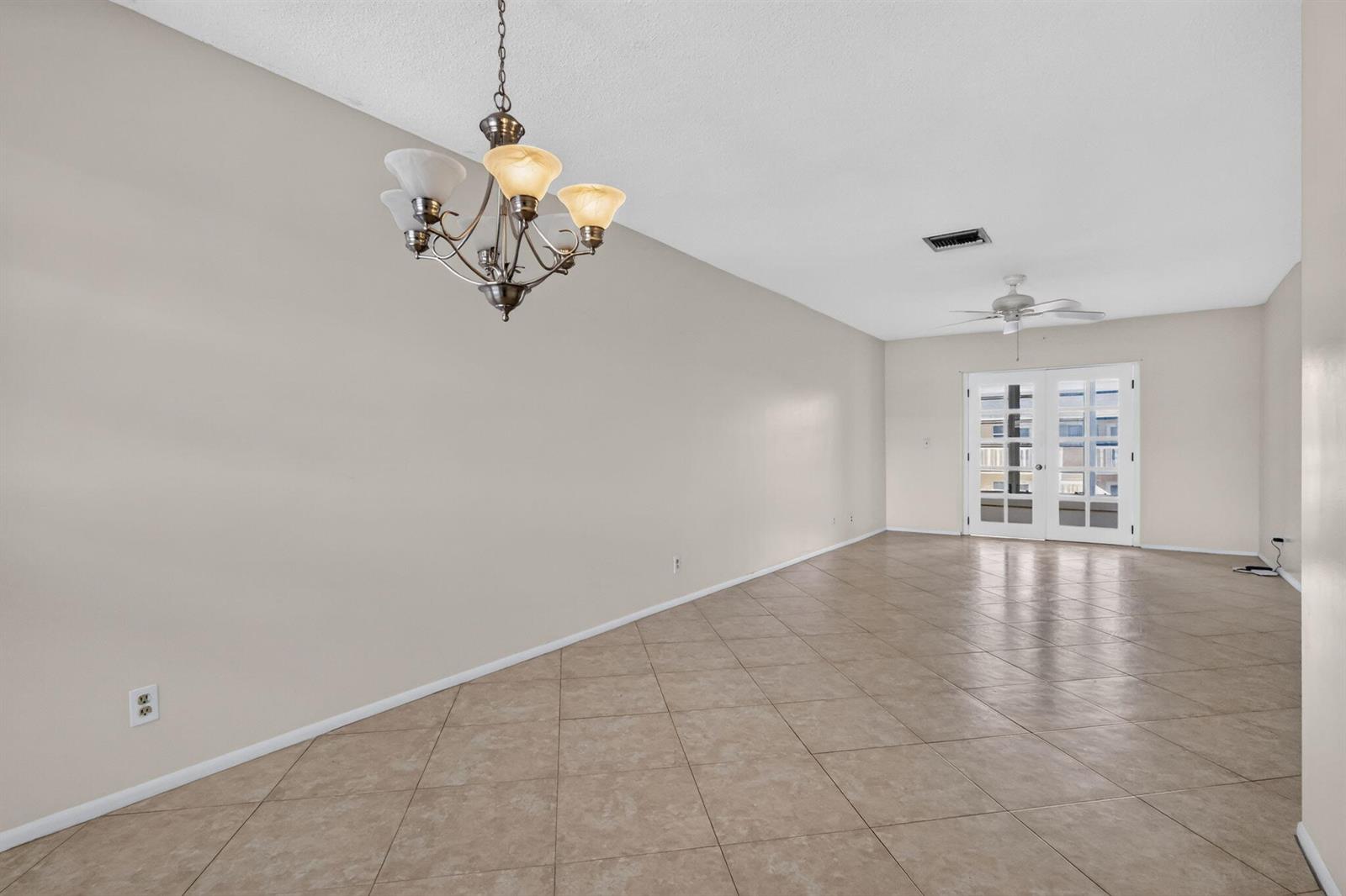 An empty room features beige walls, a chandelier, a ceiling fan, and diagonal tile flooring — 2182 NE 1st Way # 202, Boynton Beach FL 33435, BOYNTON BEACH, FL