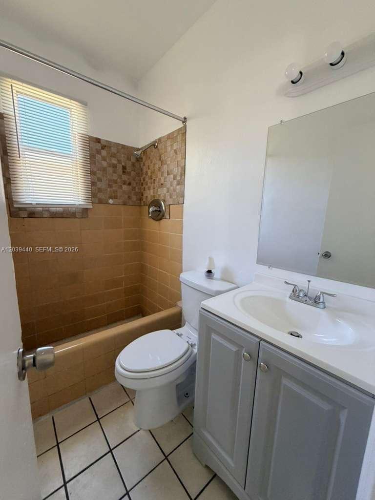 A bathroom features a gray vanity, a white toilet, and a tan tiled shower area — 1844 Taft St # 5, Hollywood FL 33020, HOLLYWOOD, FL