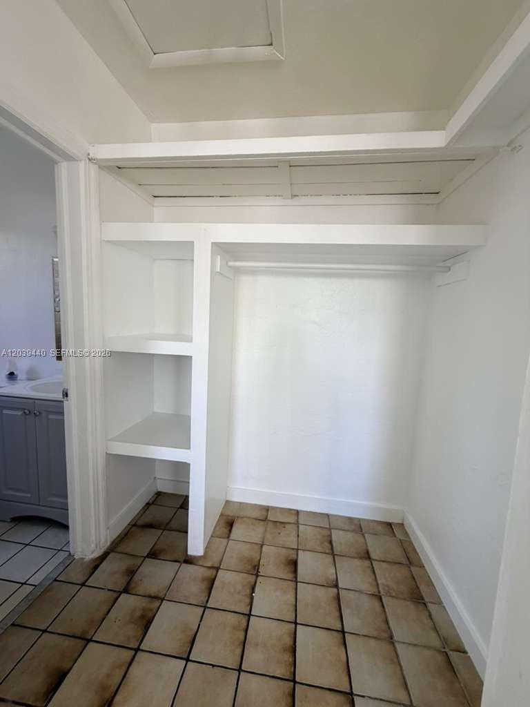 A closet with built-in shelving and a hanging rod features tile flooring — 1844 Taft St # 5, Hollywood FL 33020, HOLLYWOOD, FL