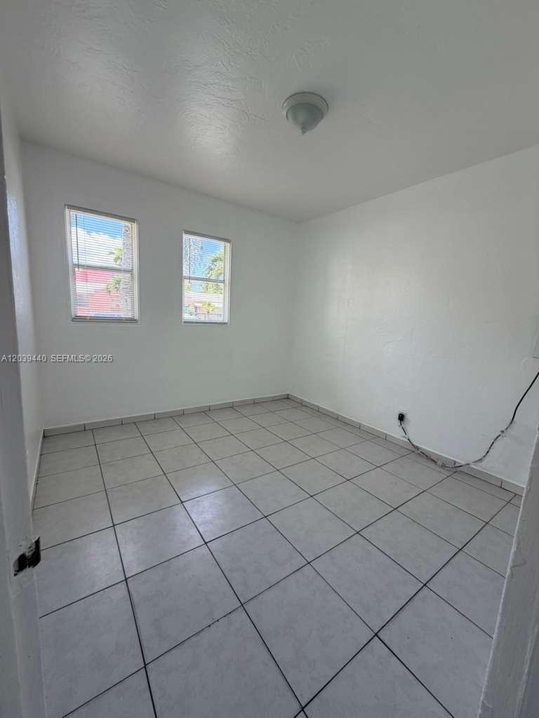 An empty room features white walls, light-colored tile flooring, two windows, and a ceiling light — 1844 Taft St # 5, Hollywood FL 33020, HOLLYWOOD, FL