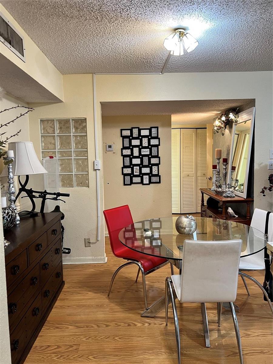 A dining area features a glass table, mixed-color chairs, a dark dresser, and glass blocks — 708 SE 2nd Avenue # 428, Deerfield Beach FL 33441, DEERFIELD BEACH, FL