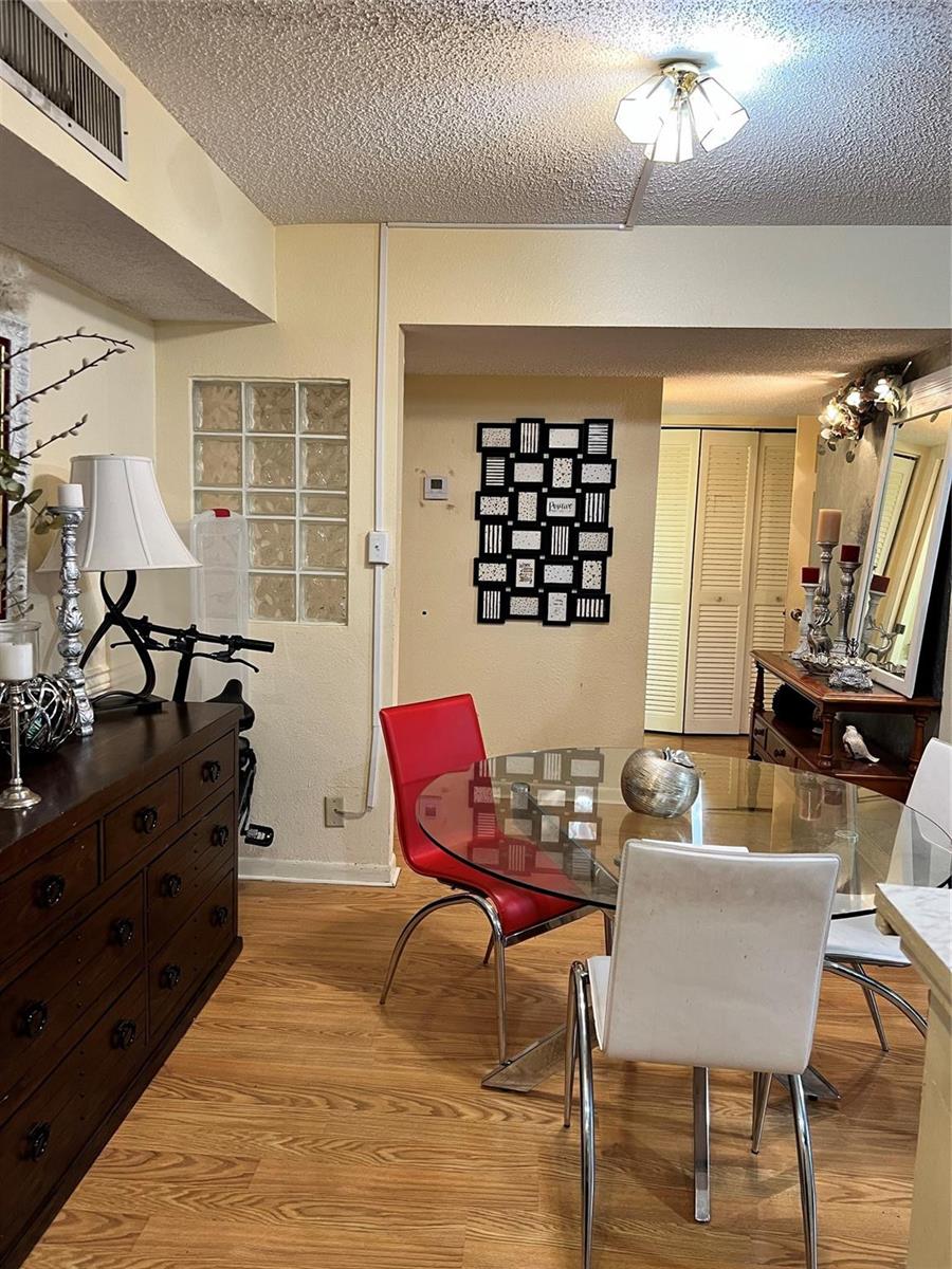 A dining area features a glass-topped table, red and white chairs, and a dark wood dresser — 708 SE 2nd Avenue # 428, Deerfield Beach FL 33441, DEERFIELD BEACH, FL