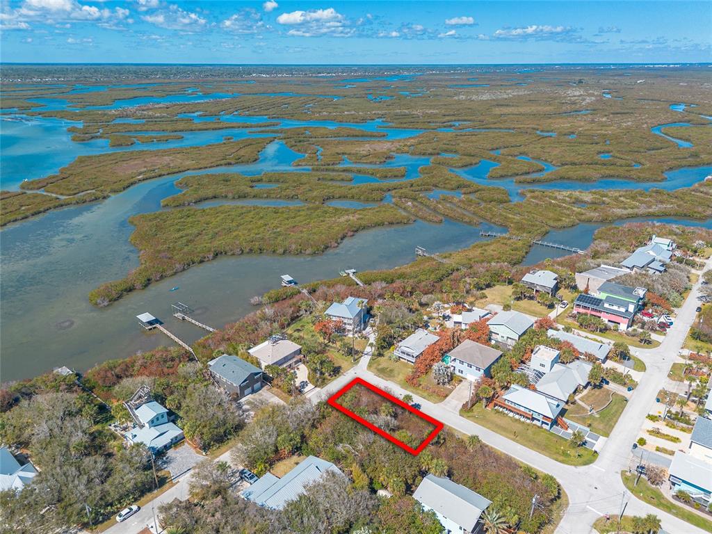 An aerial view shows a vacant rectangular lot outlined in red within a coastal neighborhood — RIVER ROAD, NEW SMYRNA BEACH, FL