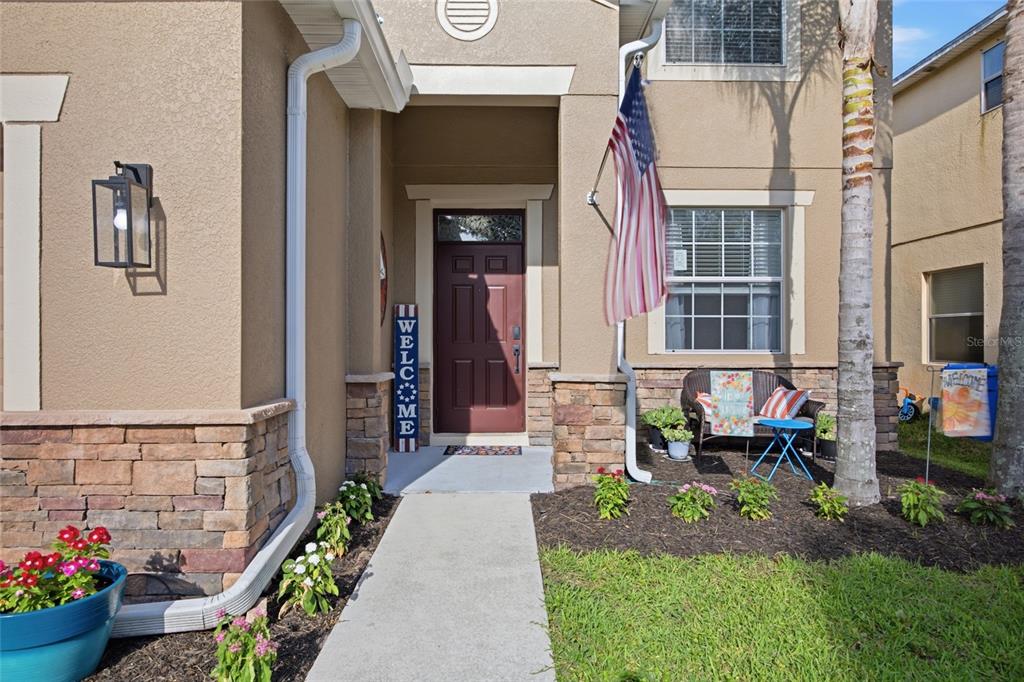 The exterior of a house features a stone-accented facade, a front walkway, and an American flag — 15410 DAKOTA SKY PLACE, SUN CITY CENTER, FL