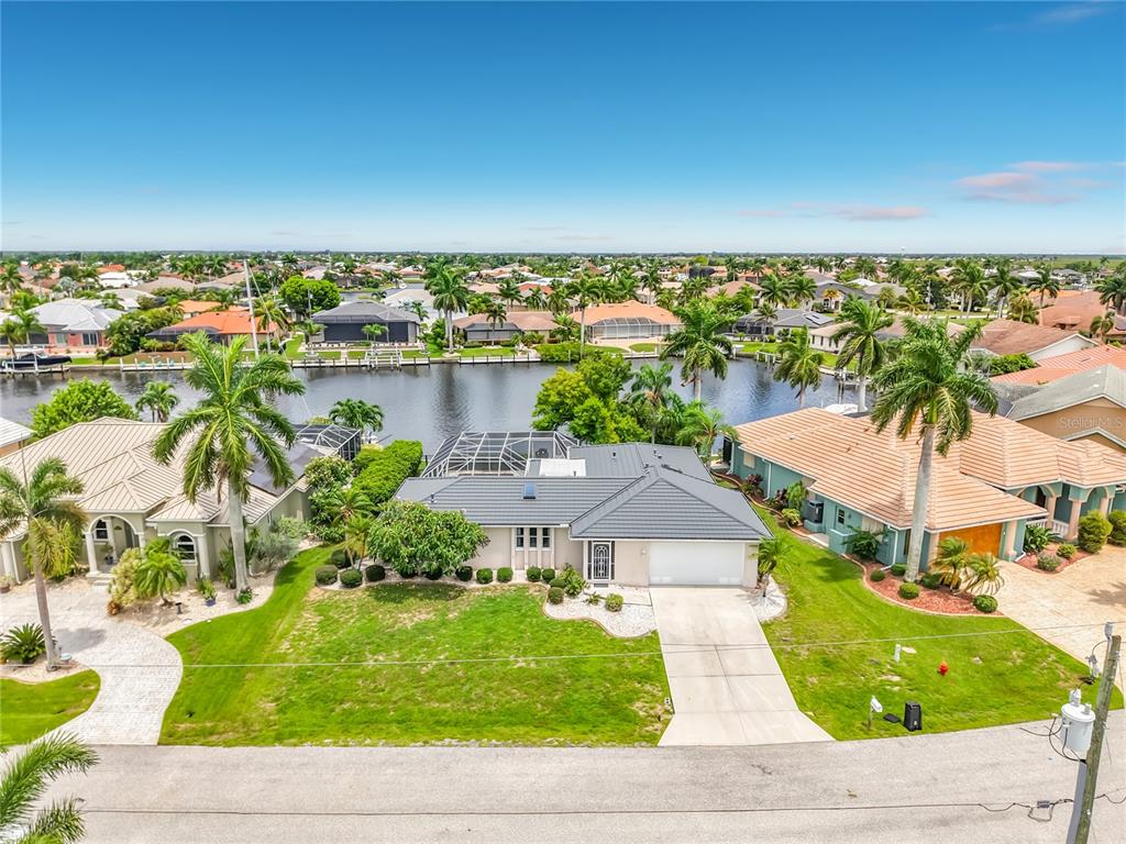 An aerial view shows a single-story house with a gray roof, driveway, and backyard pool — 1438 SEA FAN DRIVE, PUNTA GORDA, FL