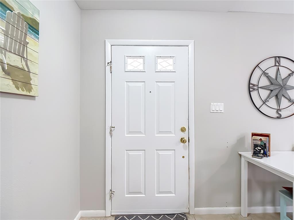 A white front door with two small windows is centered on a light gray wall — 1438 SEA FAN DRIVE, PUNTA GORDA, FL