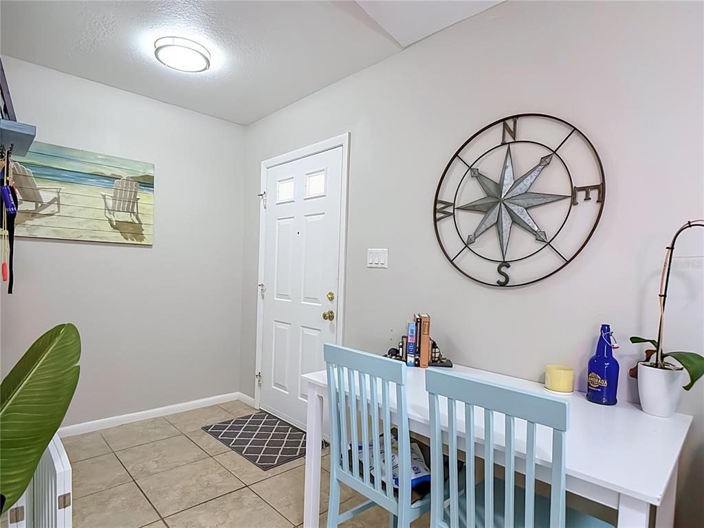 An entryway features tile flooring, a white door, a compass wall decoration, and a dining table — 1438 SEA FAN DRIVE, PUNTA GORDA, FL