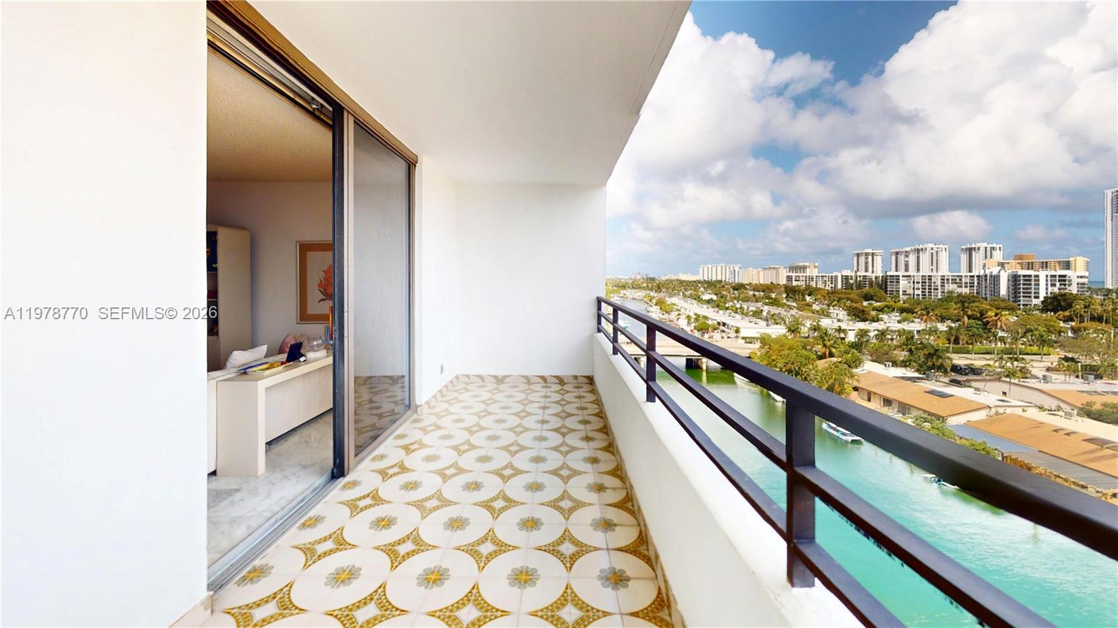 A balcony with patterned tile flooring overlooks a canal and city skyline — 2500 PARKVIEW DR # 902, Hallandale Beach FL 33009, HALLANDALE BEACH, FL