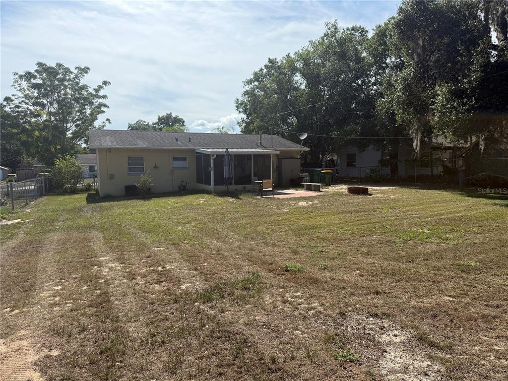 A single-story house with a screened-in porch sits on a large, grassy backyard lot — 37 PINE STREET, EUSTIS, FL