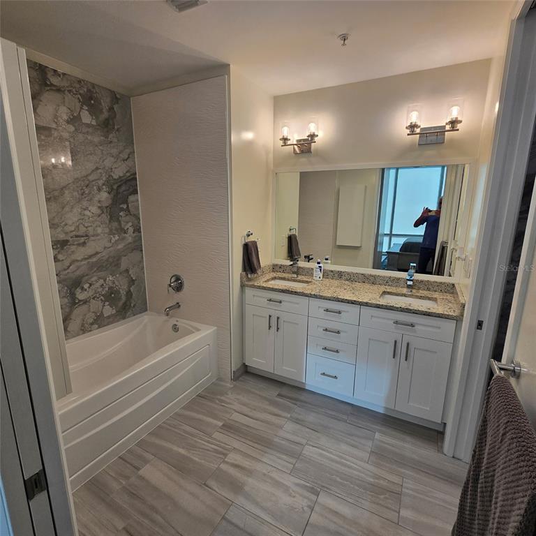 A bathroom features a white vanity with double sinks, a soaking tub, and tiled flooring — 150 E ROBINSON STREET UNIT 2409, ORLANDO, FL