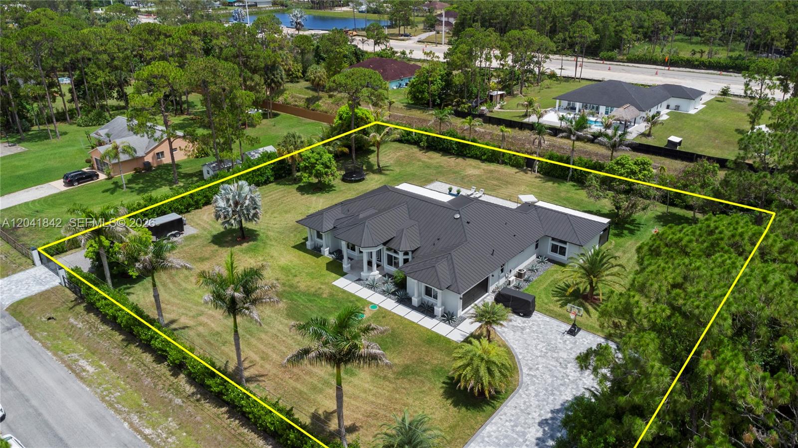 An aerial view shows a single-story house with a dark metal roof and large yard — 15436 N 92nd Ct N, Palm Beach FL 33412, PALM BEACH, FL