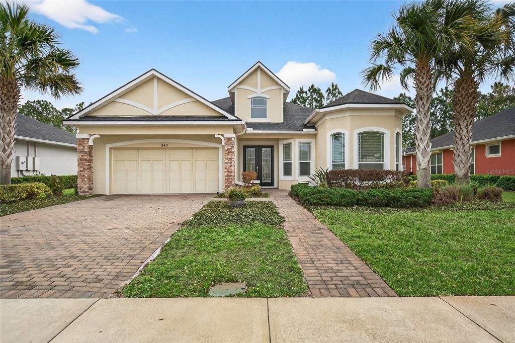 A single-story house with a beige exterior, a two-car garage, and a brick paver driveway — 349 CHELSEA PLACE AVENUE, ORMOND BEACH, FL